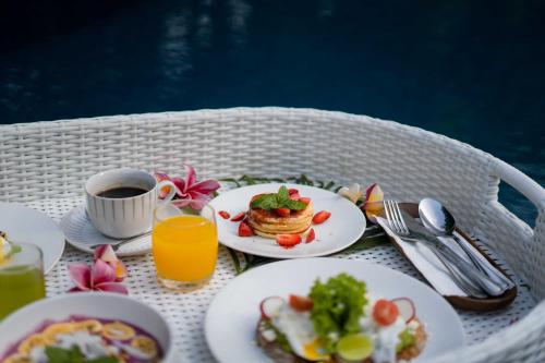 een tafel met borden eten en een kopje koffie bij Penida Green Palm Cottage by Bali Cabin in Toyapakeh