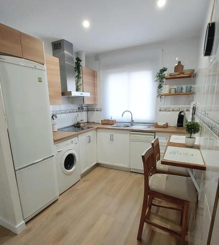 a kitchen with white appliances and a table and chairs at Apartamento Sotavento - 2 dormitorios in Chipiona