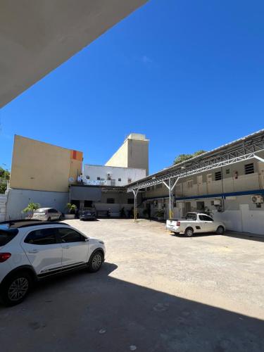 Dos coches estacionados en un estacionamiento frente a un edificio. en Hotel Maceió 3 irmãos, en Juazeiro do Norte