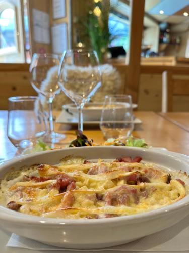 a plate of food on a table with wine glasses at Hôtel-Chalet les Mélèzes in Valloire