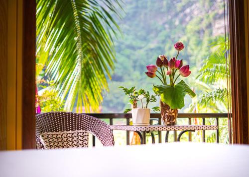 a table with a vase of flowers and a window at Hoang Minh Mountainside Villa in Ninh Binh