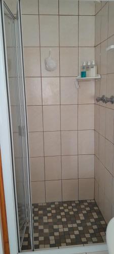 a shower with a glass door in a bathroom at Our Little House in Franskraalstrand