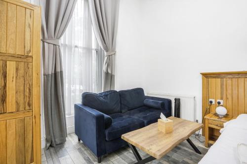 a living room with a blue couch and a table at BeiRoom Hyde Park Apartments in London