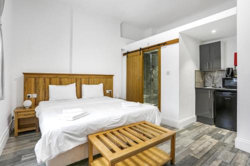 a bedroom with a large bed with a wooden headboard at BeiRoom Hyde Park Apartments in London