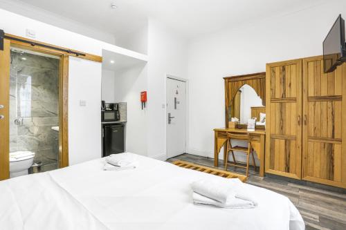 a bedroom with a bed and a desk and a bathroom at BeiRoom Hyde Park Apartments in London
