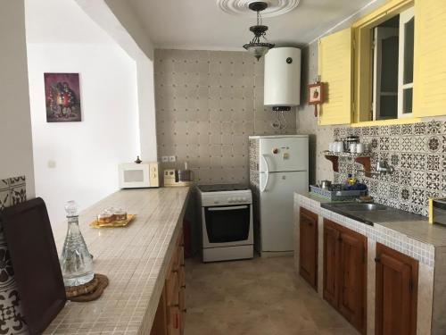 a kitchen with a white refrigerator and a stove at Villa des Jasmins - Aghroude in Aghroude