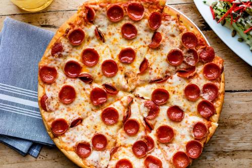 a pepperoni pizza sitting on top of a wooden table at Hotel Lulu in Round Top