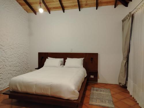 una camera da letto con un letto grande con lenzuola bianche di Tierra Descanso Ecorural a Paipa