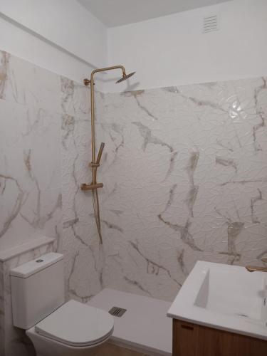 a bathroom with a toilet and a marble wall at Monte Gordo Beach Sky Flat in Monte Gordo