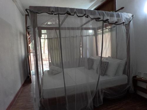 a bedroom with a canopy bed with white pillows at Tree Nest Sigiriya in Kibissa