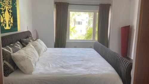 a bedroom with a white bed with a window at 2 Zimmerwohnung, offene Küche und grosser Wohnbereich mit Poolblick in Cabarete wenige Schritte vom Meer in Cabarete