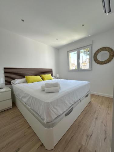 a white bedroom with a large white bed with yellow pillows at Calahonda Delux in Sitio de Calahonda