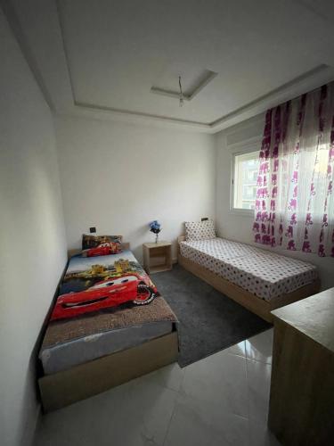 Un dormitorio con dos camas y una ventana. en Riad Sofia Martil, en Martil