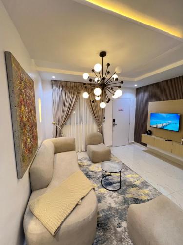 a living room with a couch and a chandelier at Danagewhitehouseapartment in Ankuru