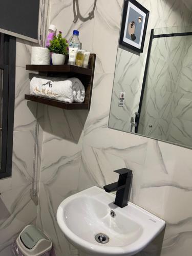 a white bathroom with a sink and a mirror at Morgan Hill Residence in Abuja