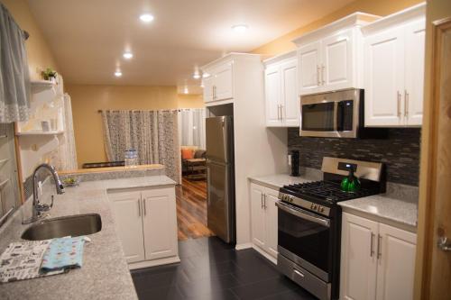 a kitchen with white cabinets and a black stove top oven at Upstairs 3 Bedroom Avalon Regia Apartment in Georgetown