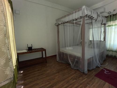a bedroom with a canopy bed and a wooden floor at Tree Nest Sigiriya in Kibissa