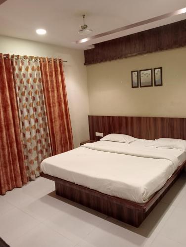 a bedroom with a large bed and a curtain at Narayani lodge नारायणी लॉज in Kolhapur
