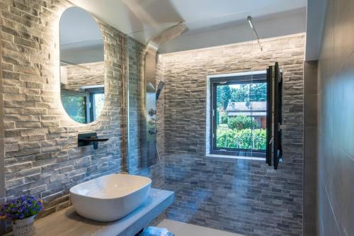 a bathroom with a white sink and a brick wall at Casa Paola in Rocca Priora