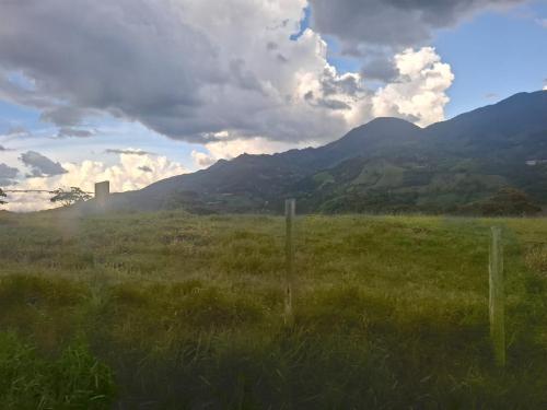 a fence in a field with mountains in the background at Cabaña sol wifi jacuzzi charcos parking in Barbosa