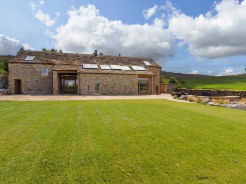 una antigua casa de piedra con un gran campo de césped en Carden Laithe Barn, en Skipton