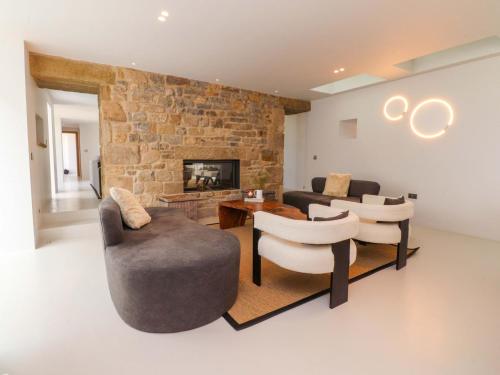 Una sala de estar con sofás y sillas y una chimenea. en Carden Laithe Barn, en Skipton