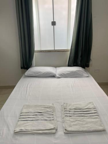 a bed with two towels on it with a window at Loft Cantinho do Amor in Rio das Ostras