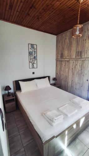 a bedroom with a white bed with a wooden wall at Olivo Apartment - Studio in Lixouri