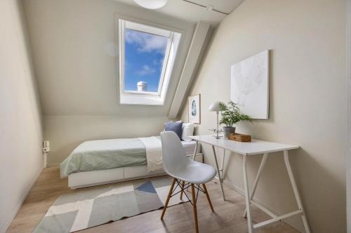 a bedroom with a bed and a desk and a window at Top-Floor Gem with City Views in Bergen
