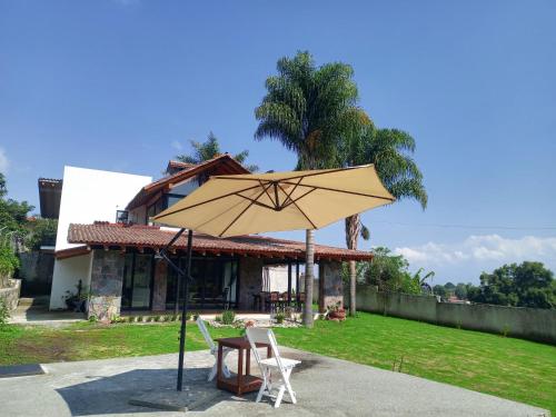 a table and chairs and an umbrella in front of a house at Hotel Campestre, Valle de Bravo in Valle de Bravo