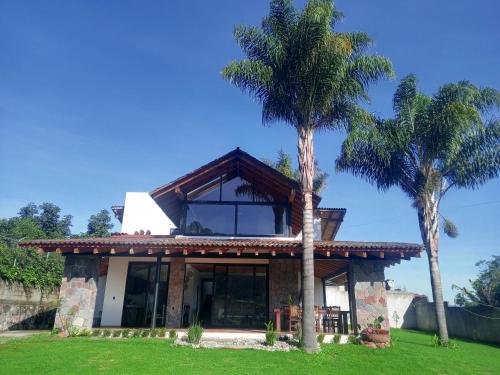 a house with two palm trees in front of it at Hotel Campestre, Valle de Bravo in Valle de Bravo