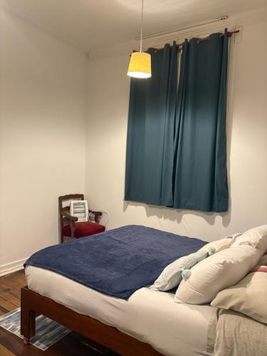 a bedroom with a bed with a blue blanket and a window at BbCasita Yellow in Valparaíso