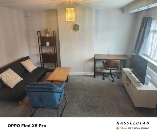 a living room with a couch and a table and a desk at Stunning maisonette available in Watford