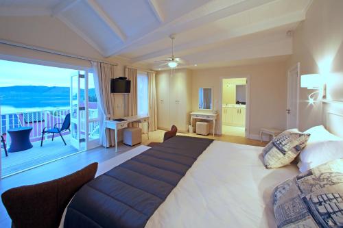 a bedroom with a large bed and a balcony at Westhill Luxury Guest House in Knysna