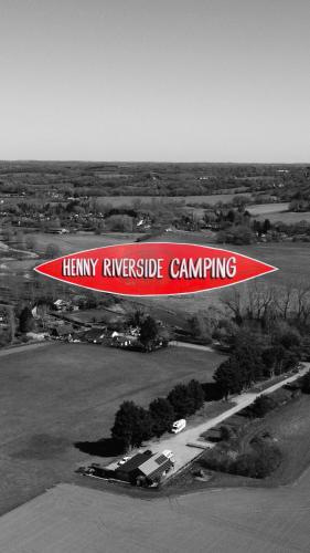a red and white sign flying over a field at Henny Riverside Glamping in Sudbury