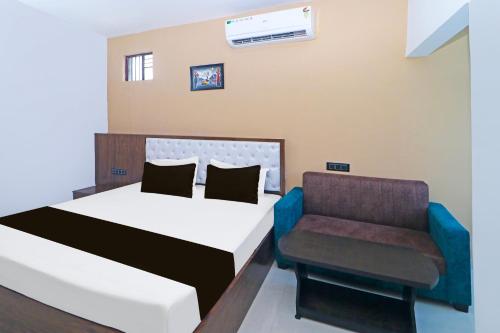 un dormitorio con una cama y una silla en Hotel O MG International, en Jamshedpur