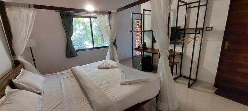 a bedroom with a bed with white sheets and a window at Hotel O Citrus Resort in Āmbavna