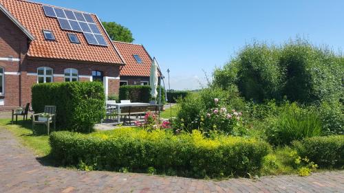 a garden in front of a building with a house with solar panels at Ferienwohnungen Zollhaus Utlandshoern in Norden