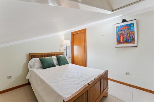 a bedroom with a bed with white sheets and green pillows at GuestReady - Lovely escape in the countryside in Aveiro