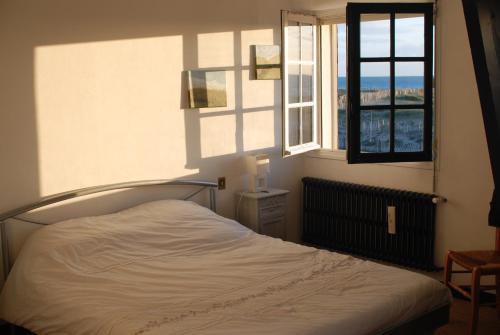 une chambre avec un lit et deux fenêtres dans l'établissement Villa Dumont D'urville, à La Turballe