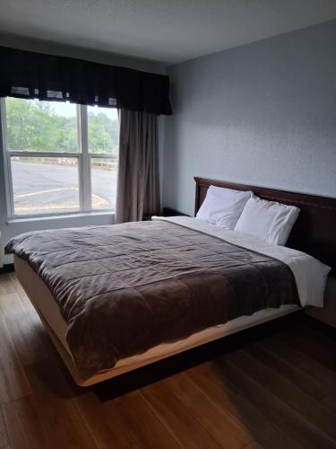 a bed in a bedroom with a large window at Lakeview Inn in Lake Saint Louis