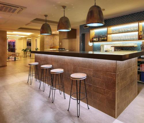 a bar in a restaurant with stools at Agua Hotels Vila Branca in Lagos