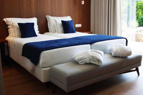 two beds in a hotel room with towels on a bench at Agua Hotels Mondim de Basto in Mondim de Basto