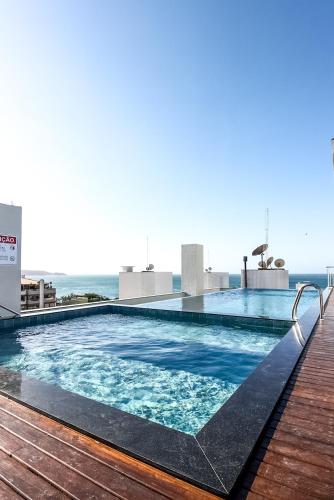 a swimming pool on top of a building with the ocean in the background at Flats Four Seasons by RD Stays in Bombinhas
