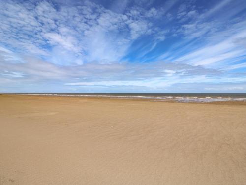 a sandy beach with a blue sky and the ocean at Sandy Toes in Mablethorpe