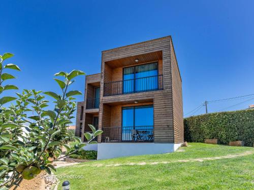 a brick house with a balcony on a clear day at Ericeira Coxos Beach Lodge in Santo Isidoro