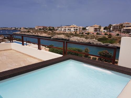 a swimming pool on a balcony with a view of the water at Agua en las Rocas in Sa Caleta