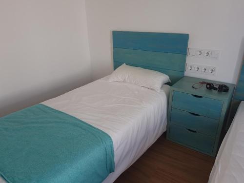 a bedroom with a bed with a blue headboard and a night stand at Agua en las Rocas in Sa Caleta
