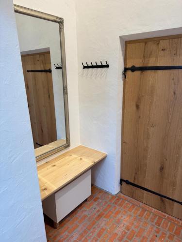 a bathroom with a mirror and a wooden door at falternhof loft - geschichte trifft auf design in Höslwang
