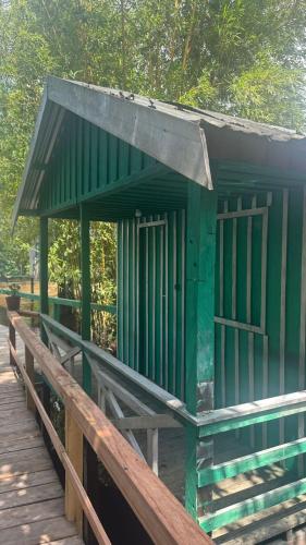 a green building on a wooden deck with trees at Flor da Mata in Iranduba